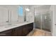 Modern bathroom featuring double sinks, dark wood cabinets, and a glass-enclosed shower at 26657 W Renee Dr, Buckeye, AZ 85396