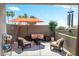 Outdoor balcony with seating around a fire pit and shade provided by an orange umbrella at 28404 N 67Th St, Cave Creek, AZ 85331