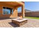 Close up of the outdoor fire pit on the brick patio with a view of the home's window at 30804 N 120Th Ave, Peoria, AZ 85383