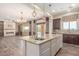 Open-concept kitchen with granite island, modern lighting, dark wood cabinets, and view into living area at 30804 N 120Th Ave, Peoria, AZ 85383