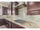 Close-up of kitchen with granite countertops, tile backsplash, stainless steel range hood, and dark cabinetry at 30804 N 120Th Ave, Peoria, AZ 85383