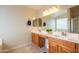 Bright bathroom featuring dual sinks, wood cabinets, a large mirror, and a shower at 3581 W Mineral Butte Dr, San Tan Valley, AZ 85144