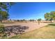 Community sand volleyball court surrounded by green grass and mature shade trees at 3581 W Mineral Butte Dr, San Tan Valley, AZ 85144