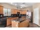 Well-lit kitchen featuring stainless steel appliances, wooden cabinetry, and a large island with a stone countertop at 35973 W Velazquez Dr, Maricopa, AZ 85138