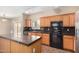 Kitchen with wood cabinets, black appliances and sliding glass door letting in natural light to brighten the space at 35973 W Velazquez Dr, Maricopa, AZ 85138