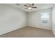 A cozy bedroom featuring neutral gray walls, ceiling fan, and a bright window at 4865 E Princess Dr, Mesa, AZ 85205