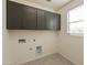 Modern laundry room with stylish gray cabinets above washer and dryer hookups at 4948 W Walatowa St, Laveen, AZ 85339