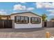 The house has many windows with black shutters, gravel landscaping, and privacy fencing at 525 S 99Th St, Mesa, AZ 85208