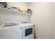 Bright laundry room features a white washer, dryer, and shelving unit above for storage at 5360 S 98Th Pl, Mesa, AZ 85212