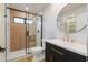 Modern bathroom featuring a glass-enclosed shower and a round mirror above the vanity at 5449 E Cambridge Ave, Phoenix, AZ 85008