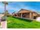 Backyard features lush green grass, desert landscaping, a covered patio, and desert trees at 7118 E Juanita Ave, Mesa, AZ 85209