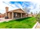 Landscaped backyard featuring a covered patio, lush grass, mature trees, and stone accents at 7118 E Juanita Ave, Mesa, AZ 85209