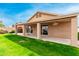 Exterior view of the home's shaded back patio and grassy backyard with lush landscaping at 7118 E Juanita Ave, Mesa, AZ 85209