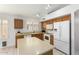 Functional kitchen with wood cabinets, white appliances, and a center island providing ample counter space at 7118 E Juanita Ave, Mesa, AZ 85209