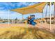 Colorful playground with a blue slide, climbing net, covered canopy, sand base, and green grassy area at 7118 E Juanita Ave, Mesa, AZ 85209