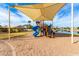 Playground featuring a blue slide, set in sand, under a shaded canopy, with palm trees and grassy areas at 7118 E Juanita Ave, Mesa, AZ 85209