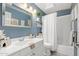 Well-lit blue bathroom with a skylight, white vanity, and a shower-tub combination at 8812 E Riviera Dr, Scottsdale, AZ 85260