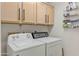 Functional laundry area with white washer and dryer units and ample above-cabinet storage space at 9039 W Wescott Dr, Peoria, AZ 85382