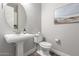 A modern powder room with a pedestal sink, toilet, round mirror and neutral color scheme at 9749 E Ripple Dr, Mesa, AZ 85212