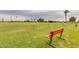 Scenic golf course view with a red bench, lush green fairways, mature trees, and blue sky at 10103 W Saddle Ridge Dr, Sun City, AZ 85373