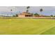 Golf course featuring a well-maintained green, decorative flags, and clubhouse in a tranquil setting at 10103 W Saddle Ridge Dr, Sun City, AZ 85373