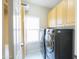 A modern laundry room features a light wood cabinets and black front loading washer and dryer at 1249 W Seascape Dr, Gilbert, AZ 85233