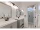 Bathroom with dual vanities, dark plumbing fixtures, decorative mirrors, and walk-in shower at 1331 E Voltaire Ave, Phoenix, AZ 85022