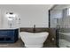 Bathroom featuring standalone tub, black fixtures, shower with custom tile, and navy vanity at 1331 E Voltaire Ave, Phoenix, AZ 85022