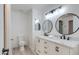 Stylish bathroom featuring a double vanity with black hardware, round mirrors, and modern lighting at 1331 E Voltaire Ave, Phoenix, AZ 85022