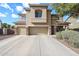 Charming two-story home with tan stucco, tile roof, three-car garage, and attractive landscaping at 14258 W Lisbon Ln, Surprise, AZ 85379