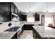 Modern kitchen with dark cabinetry, granite countertops, stainless steel appliances, and stylish backsplash at 14258 W Lisbon Ln, Surprise, AZ 85379