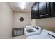 Functional laundry room with modern washer and dryer, storage cabinets, and tile floors at 14258 W Lisbon Ln, Surprise, AZ 85379