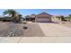 Single story home with desert landscaping, mature palm trees, and a two car garage at 15561 W Vista Grande Ln, Surprise, AZ 85374