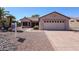 Single story home with mature landscaping, including palm trees, and a two car garage at 15561 W Vista Grande Ln, Surprise, AZ 85374