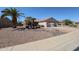Single story home with desert landscaping, including mature palm trees, and a two car garage at 15561 W Vista Grande Ln, Surprise, AZ 85374