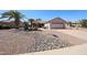 Single story home with desert landscaping, including palm trees, and a two car garage at 15561 W Vista Grande Ln, Surprise, AZ 85374
