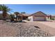 Single story home with desert landscaping, including mature palm trees, and a two car garage at 15561 W Vista Grande Ln, Surprise, AZ 85374