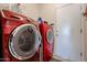 Laundry room featuring high-efficiency red washer and dryer units at 15561 W Vista Grande Ln, Surprise, AZ 85374