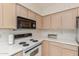 Bright kitchen featuring a microwave, oven, light wood cabinetry, and white counter tops at 18218 N 136Th Ave, Sun City West, AZ 85375