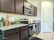 Modern kitchen featuring dark cabinets, granite countertops, stainless steel appliances, and a sleek cooktop at 18809 W Wilson St, Buckeye, AZ 85326
