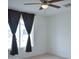 Bright bedroom featuring a ceiling fan and a large window with dark curtains at 19348 W Brave Rd, Buckeye, AZ 85326