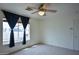 Carpeted bedroom with ceiling fan and large window with dark curtains at 19348 W Brave Rd, Buckeye, AZ 85326