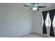 Cozy bedroom with neutral walls, a ceiling fan, and a window with dark drapes at 19348 W Brave Rd, Buckeye, AZ 85326