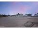 Rear exterior view showcasing the property's spacious lot, fenced area, and additional outbuildings under a colorful evening sky at 19348 W Brave Rd, Buckeye, AZ 85326