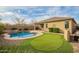 Backyard with a pool, putting green, covered patio, and lush landscaping at 20905 N Danielle Ave, Maricopa, AZ 85138