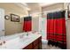 Bathroom featuring a cherry wood vanity, a large mirror, and a red and black shower curtain at 20905 N Danielle Ave, Maricopa, AZ 85138