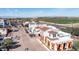 Aerial shot featuring white buildings with orange awnings and roofs, street with palm trees, and mountain backdrop at 2511 W Queen Creek Rd # 479, Chandler, AZ 85248