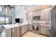 A modern kitchen featuring stainless steel appliances, gray cabinetry, and a breakfast bar overlooking the living area at 2511 W Queen Creek Rd # 479, Chandler, AZ 85248