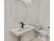 Stylish powder room with a pedestal sink, black faucet, and modern fixtures in a bright space at 26535 W Mcrae Dr, Buckeye, AZ 85396