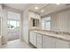 Bathroom with double sinks, granite countertop, white cabinets, and large mirror overlooking a bedroom at 26982 W Lone Cactus Dr, Buckeye, AZ 85396